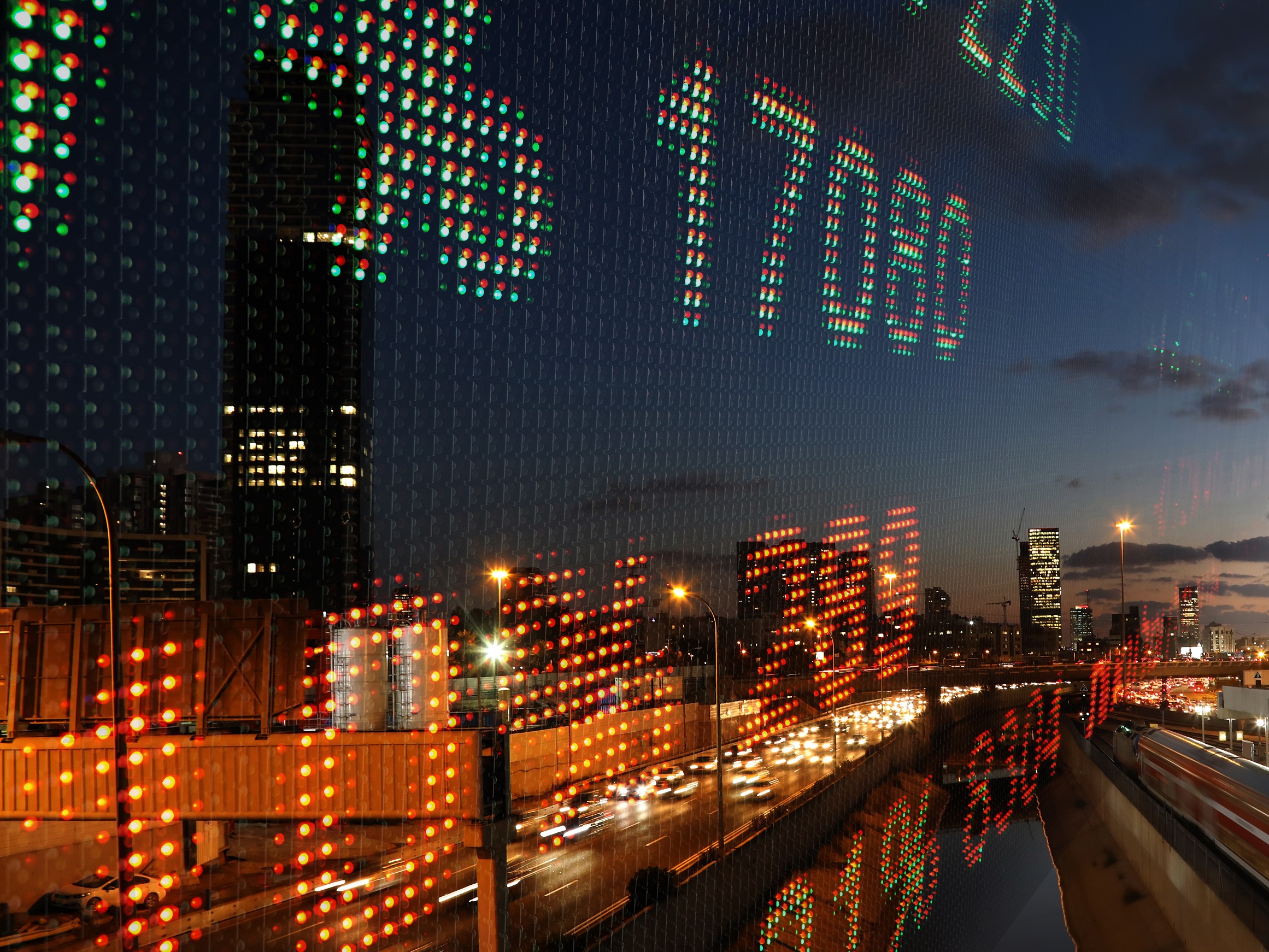 Numbers on digital screen with lit up city at night in background