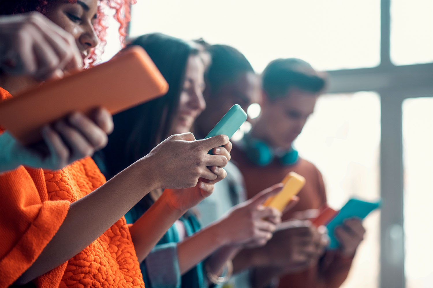 Row of people all holding and looking at their phones