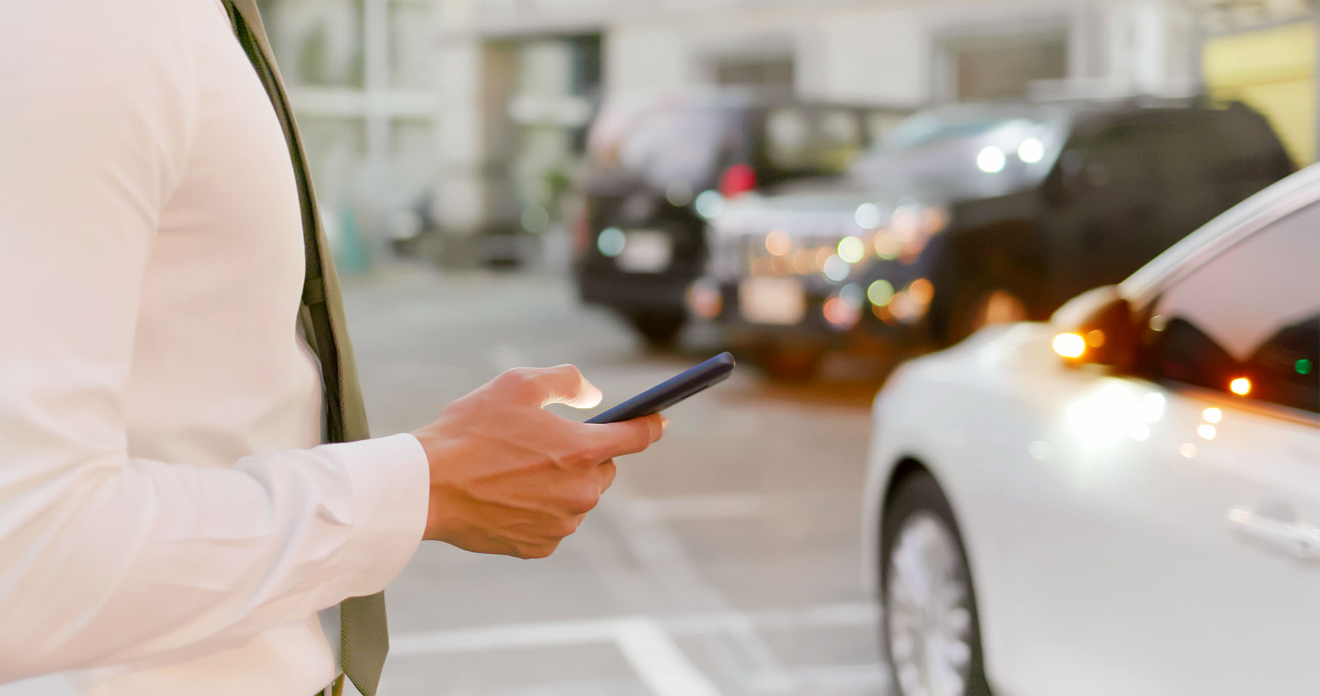 Close up view of man holding a phone next to a car