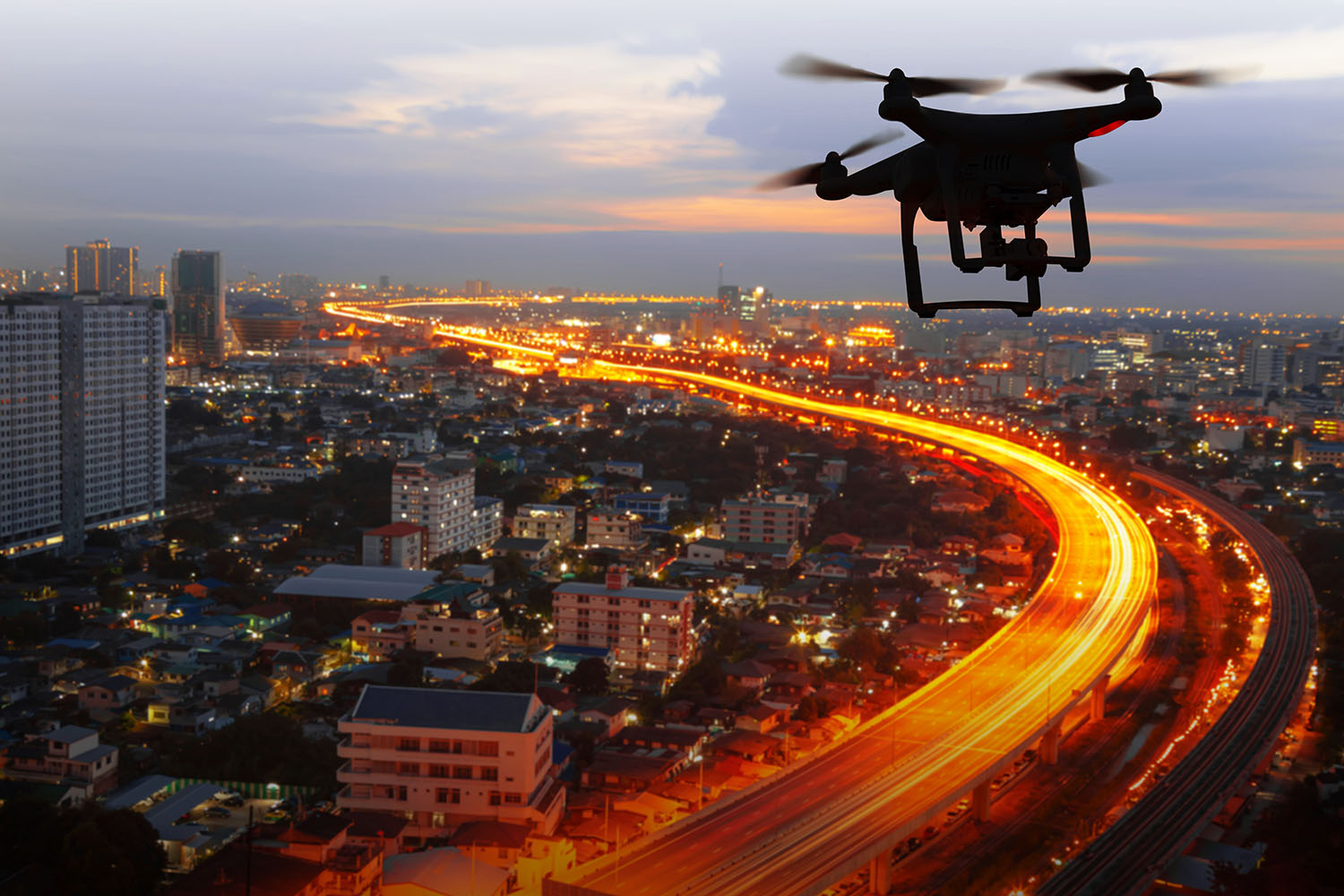 Small drone hovering over lit up city