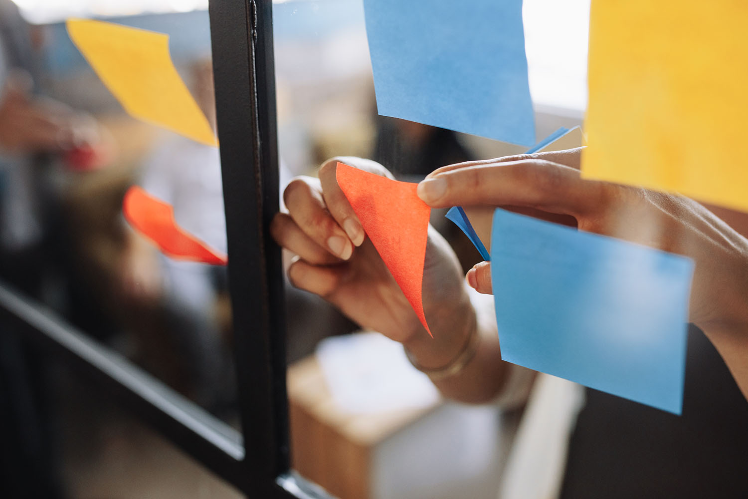 Person sticking post-it notes on a noticeboard