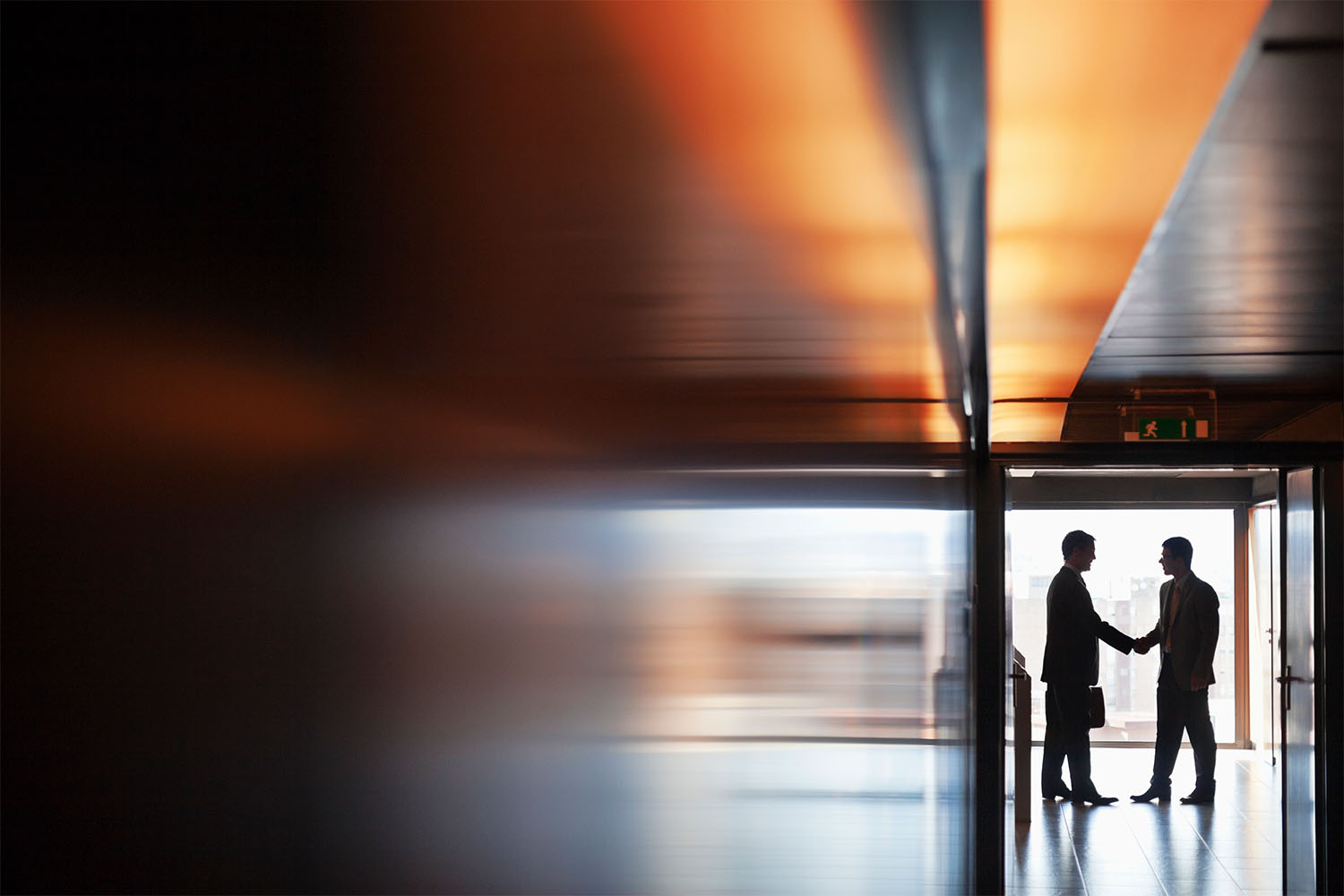 Two businessmen shaking hands in a corridor