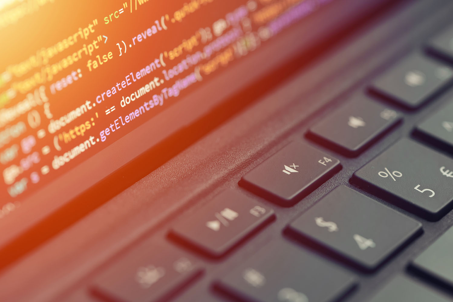 Close up view of laptop screen and keyboard, screen is showing code