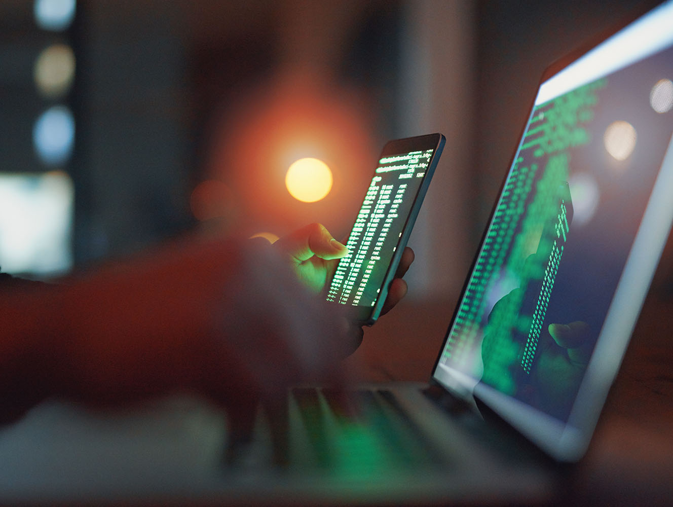 Green code on smartphone and laptop screens