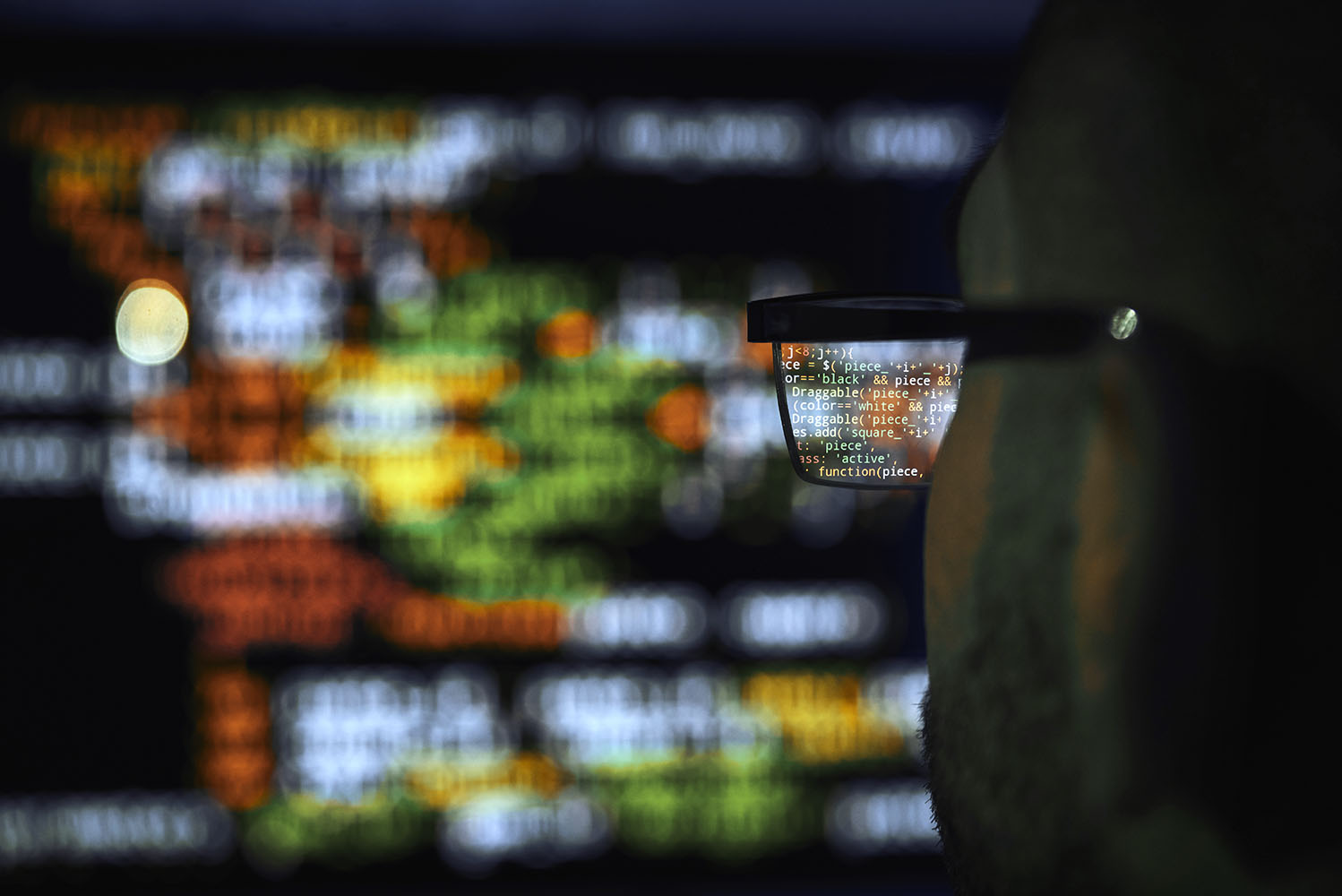 View through a man's glasses of code on a computer