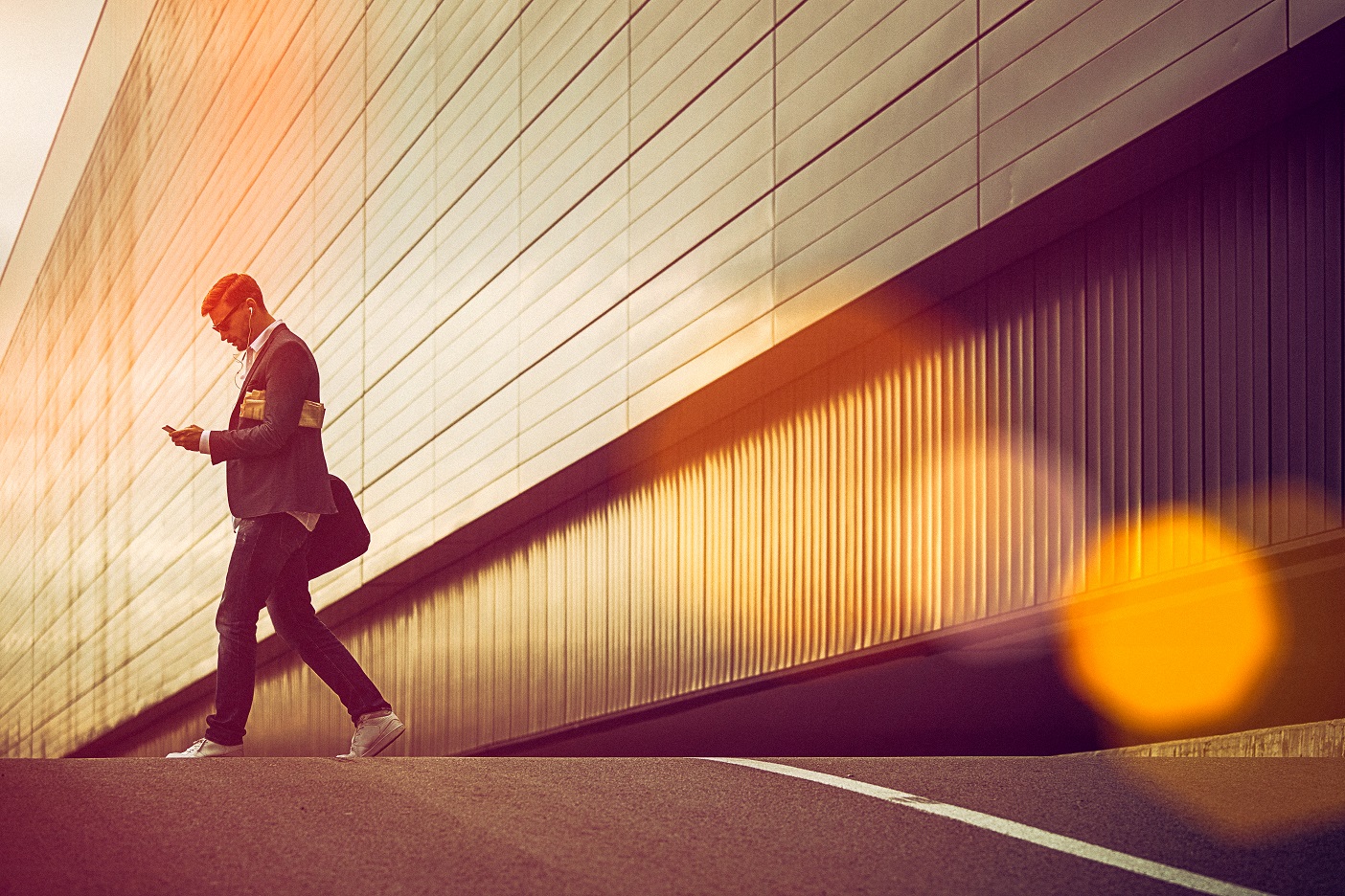 Person walking with headphones and looking at their smartphone