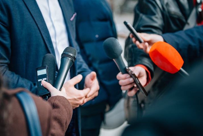 Press interview, zoomed in photo of multiple microphones pointed at a person