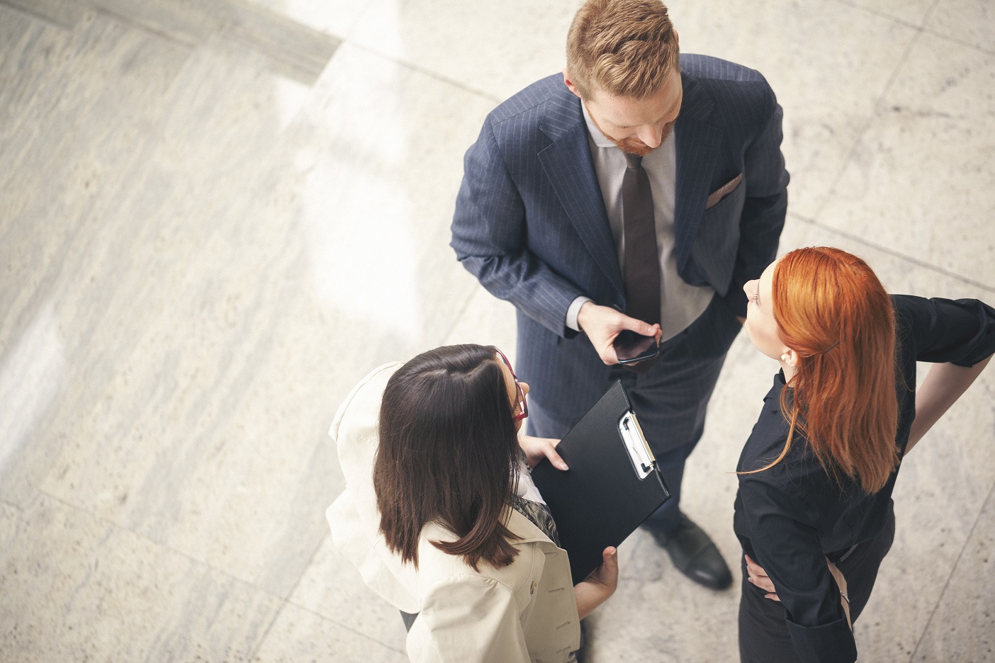 Above view of three people talking in a business setting