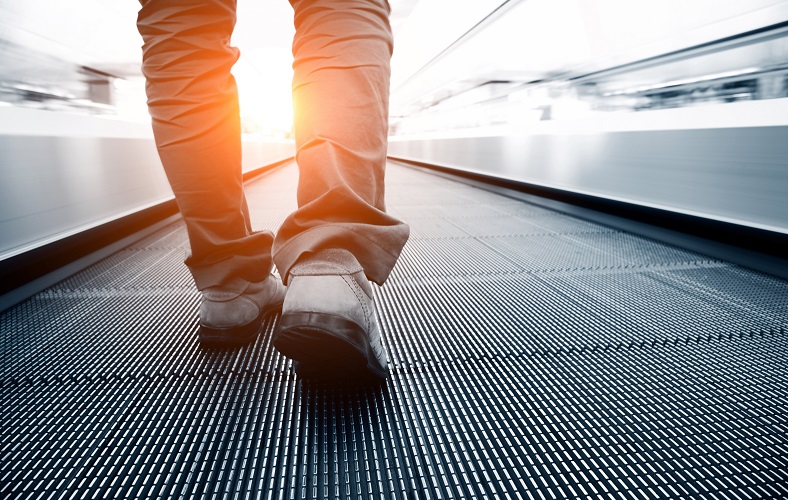Close up of a person's feet walking on a moving walkway