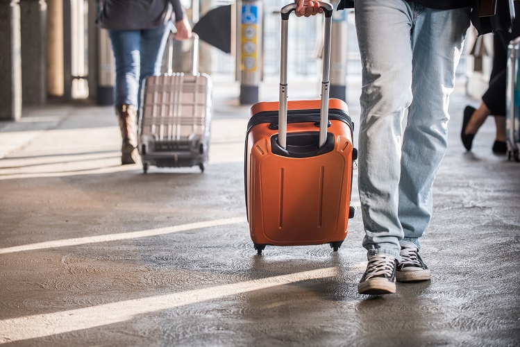 Close up of a person walking and holding a suitcase
