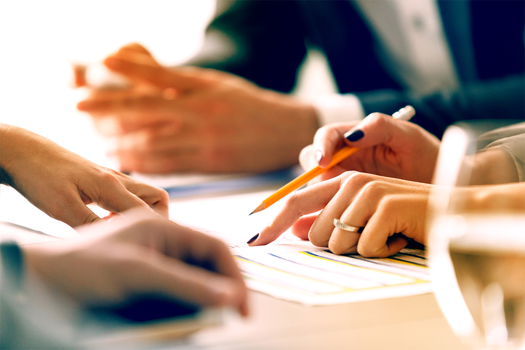 Close up of people in a meeting, hands holding pens and going over papers