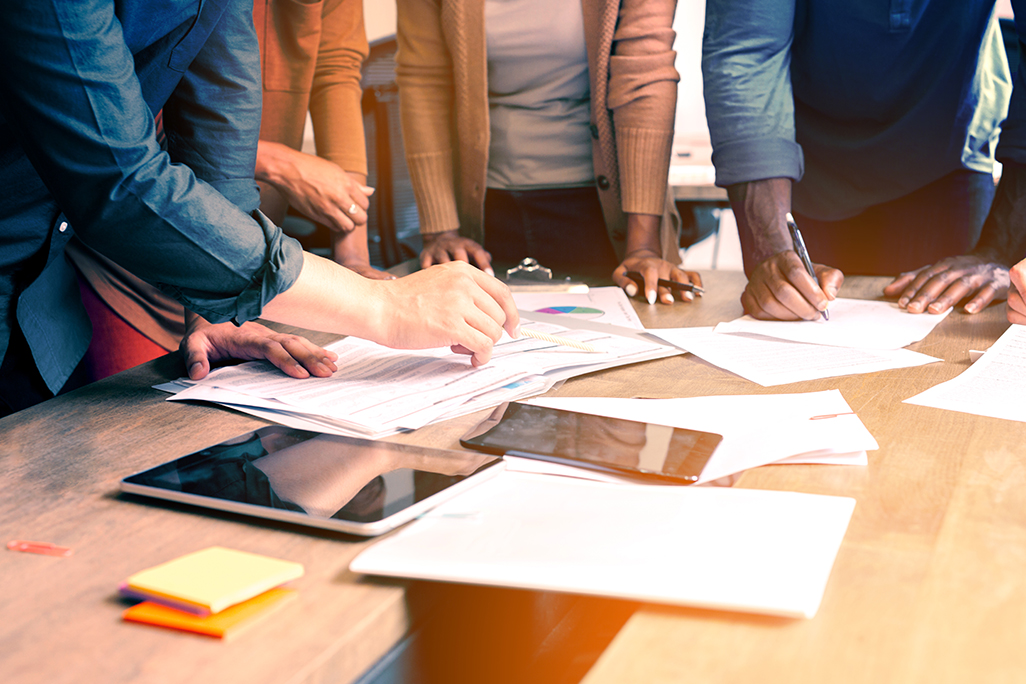 Close up of people in a meeting, hands holding pens and going over papers