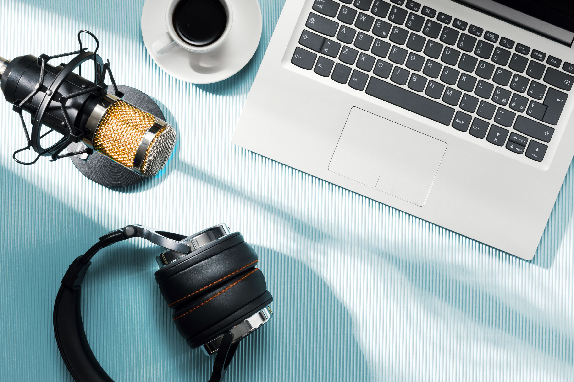 Podcaster's laptop, microphone and headphones with coffee cup