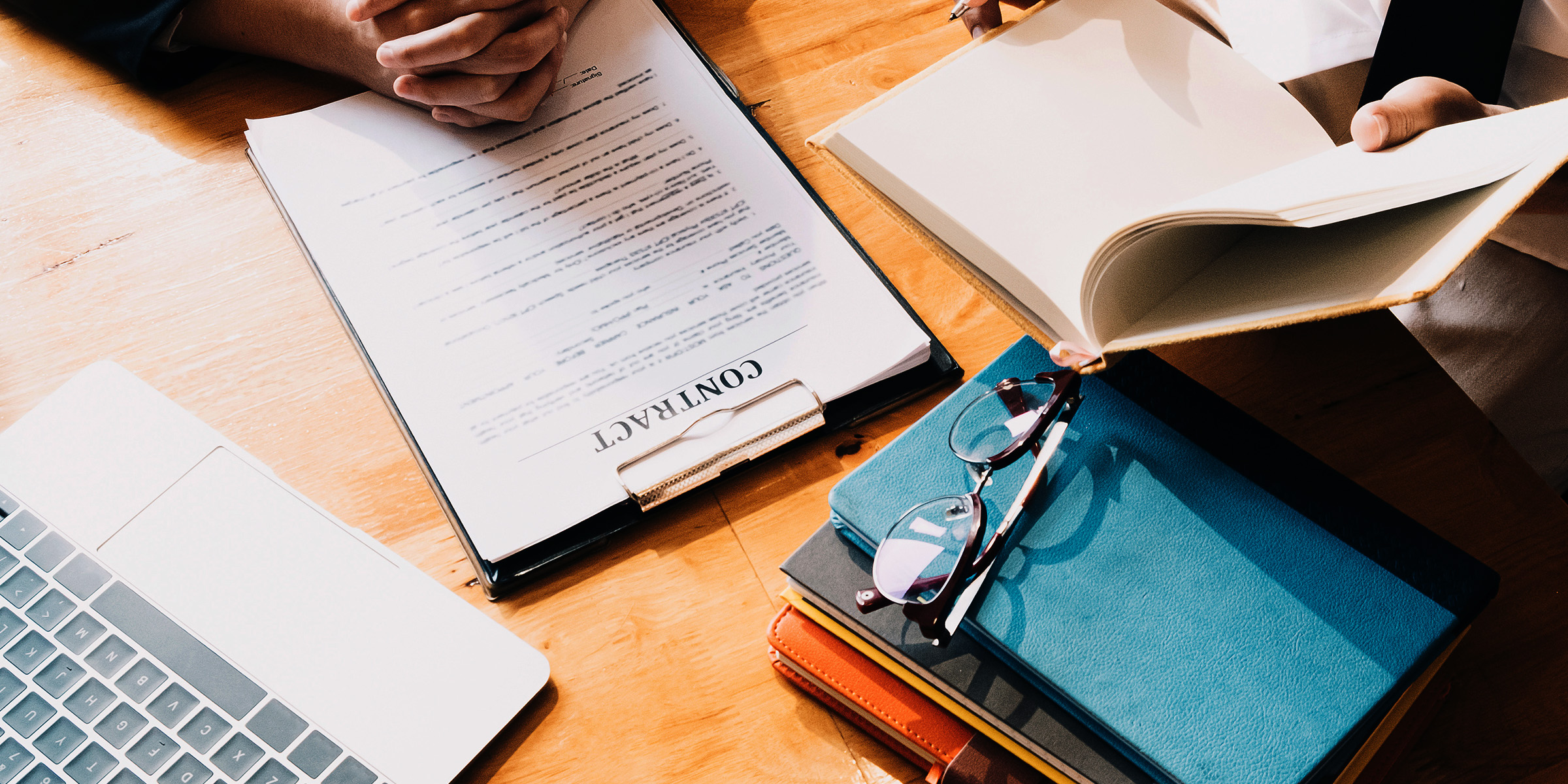 Negotiation with two people, laptop, contract for signing and notebooks