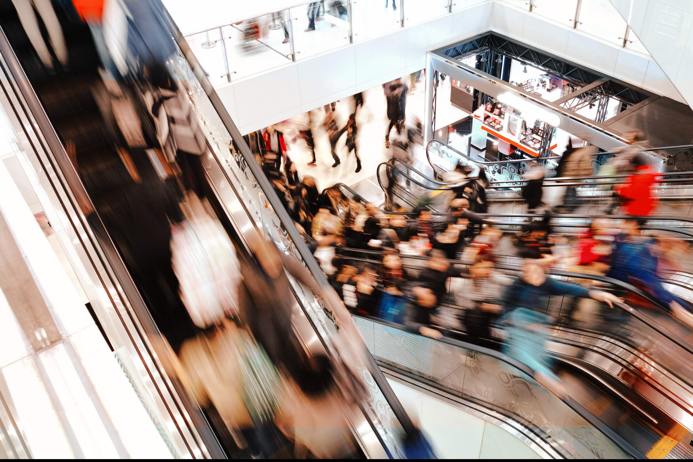 People on escalators in a shopping mall - motion blurred