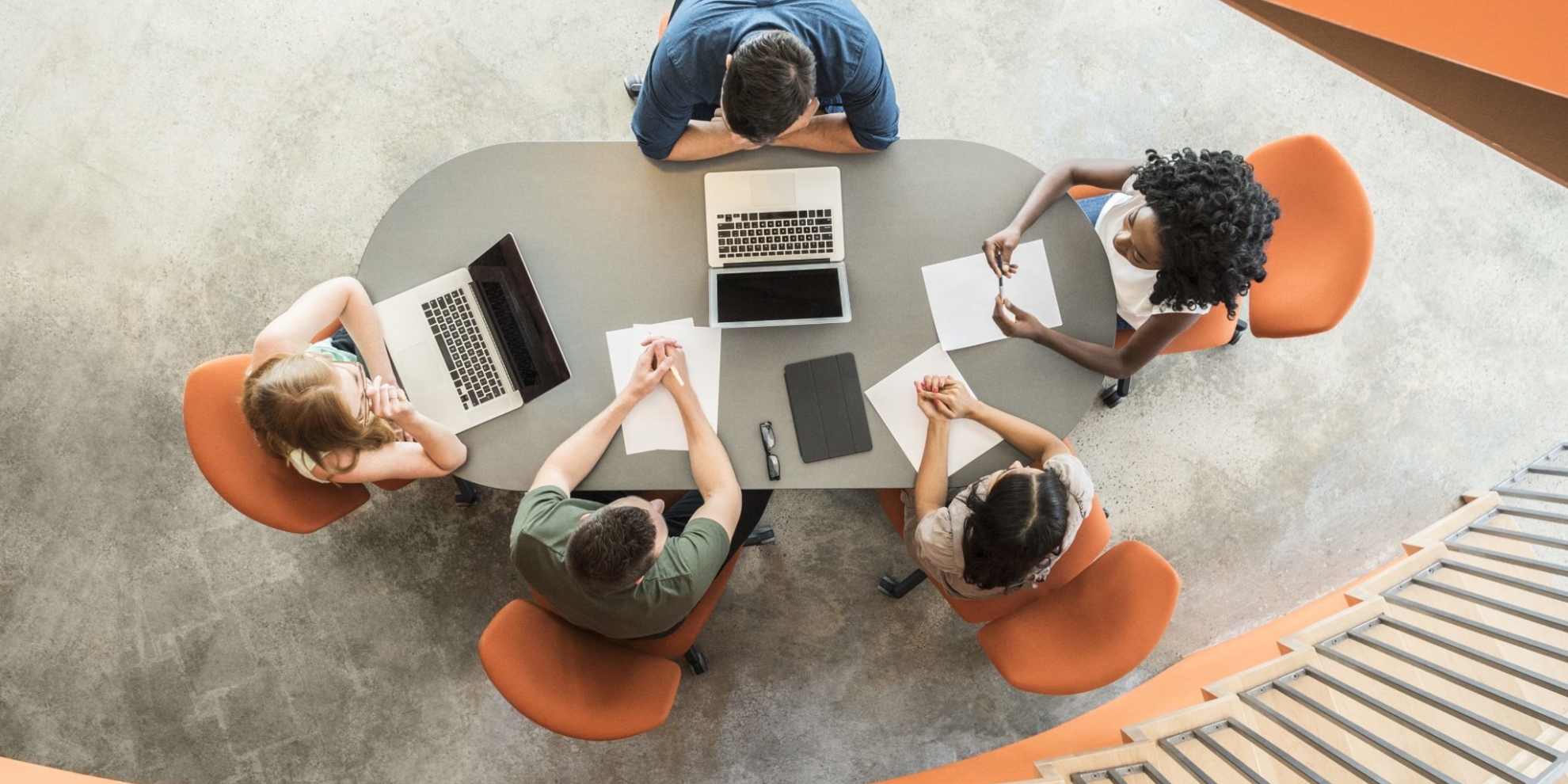 View from above towards five business people around meeting table